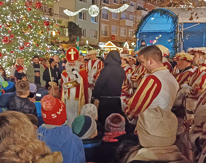 Kinder, Erwachsene, der Fanfarenzug stehen um den Nikolaus und Knecht Ruprecht herum